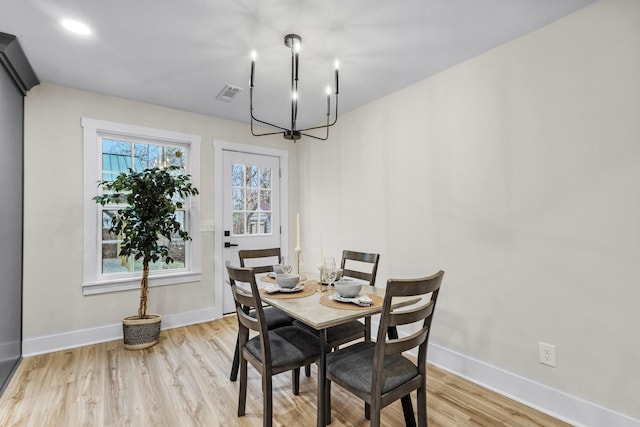 dining area with a notable chandelier, light wood-style flooring, visible vents, and baseboards