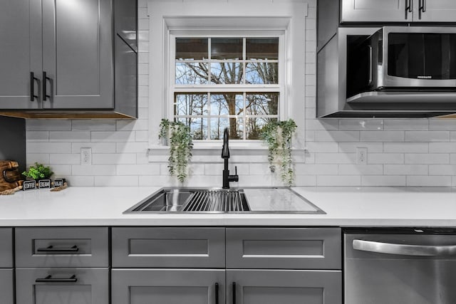 kitchen with dishwasher, a sink, and gray cabinetry