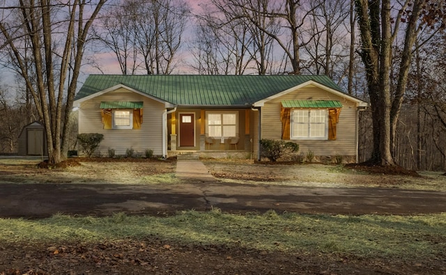 view of front of property with a porch, metal roof, an outdoor structure, and a storage unit