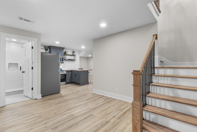 kitchen featuring light countertops, visible vents, gray cabinetry, appliances with stainless steel finishes, and light wood-style floors