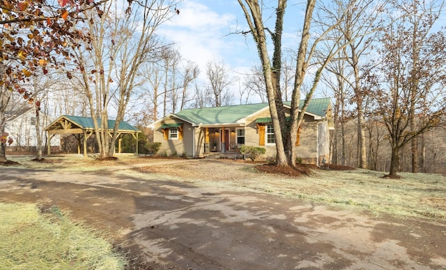 view of front of property featuring driveway, covered porch, and metal roof