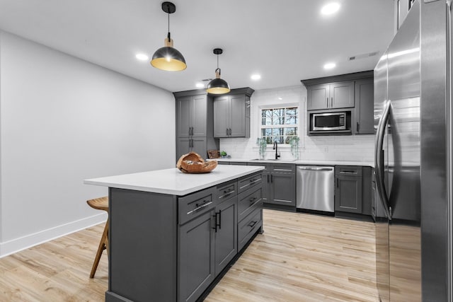 kitchen with decorative backsplash, light wood-style flooring, appliances with stainless steel finishes, gray cabinets, and light countertops