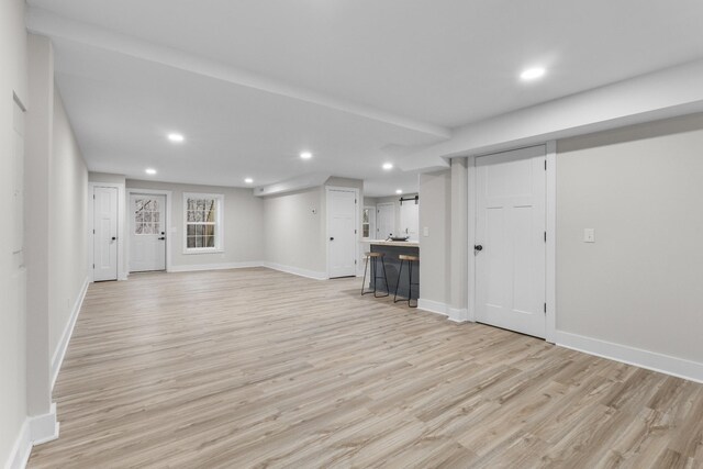 unfurnished living room with recessed lighting, baseboards, and light wood finished floors