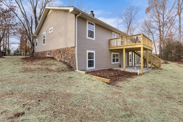 rear view of property featuring a yard, stairway, a wooden deck, a chimney, and a patio area