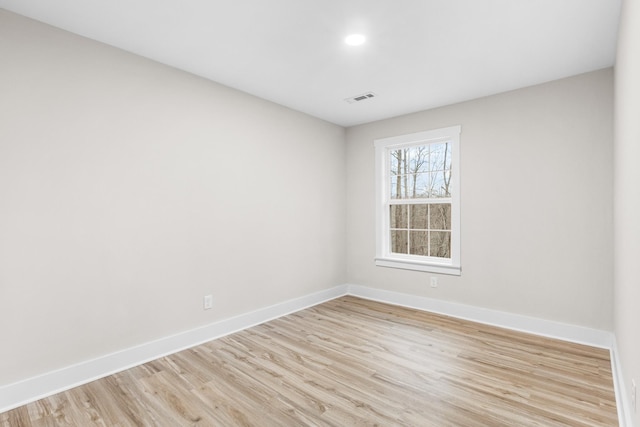 unfurnished room featuring light wood-style flooring, visible vents, and baseboards