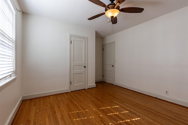 empty room featuring light wood-style flooring, baseboards, and a ceiling fan