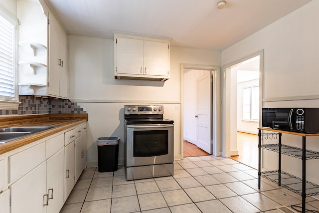 kitchen with plenty of natural light, black microwave, stainless steel electric range oven, and decorative backsplash