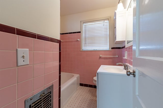 bathroom featuring a washtub, tile walls, toilet, vanity, and tile patterned floors