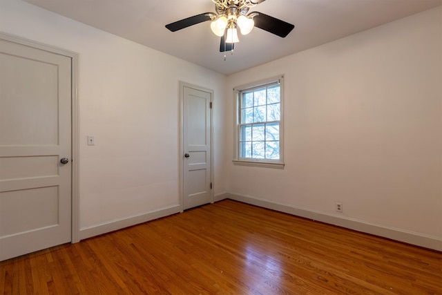 empty room with a ceiling fan, light wood-style flooring, and baseboards