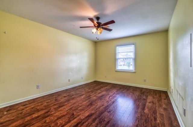 empty room featuring ceiling fan, baseboards, and wood finished floors