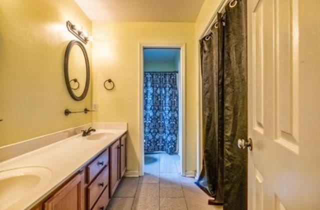 full bathroom with double vanity, a sink, and tile patterned floors