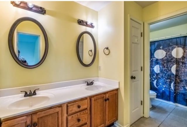 bathroom featuring tile patterned floors, a sink, toilet, and double vanity