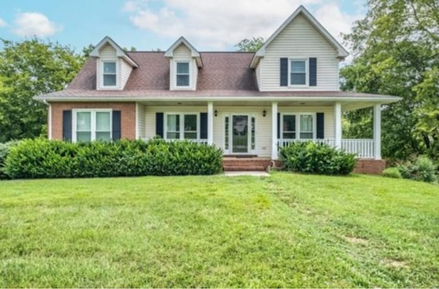 cape cod home featuring covered porch, brick siding, and a front yard