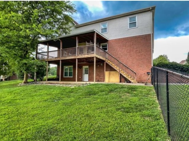 back of property with brick siding, a yard, fence, a wooden deck, and stairs