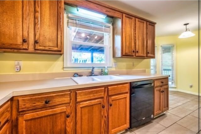 kitchen with light tile patterned floors, dishwasher, brown cabinets, light countertops, and a sink