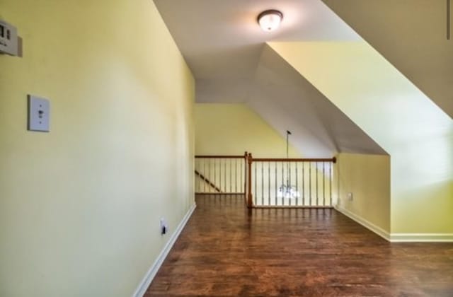 additional living space with baseboards, vaulted ceiling, and wood finished floors