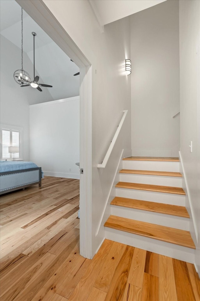 stairs featuring a towering ceiling, a ceiling fan, and wood finished floors