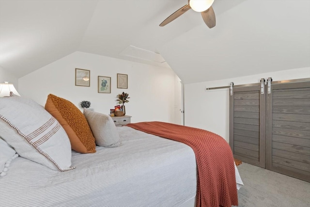 bedroom with lofted ceiling, ceiling fan, a barn door, and carpet flooring