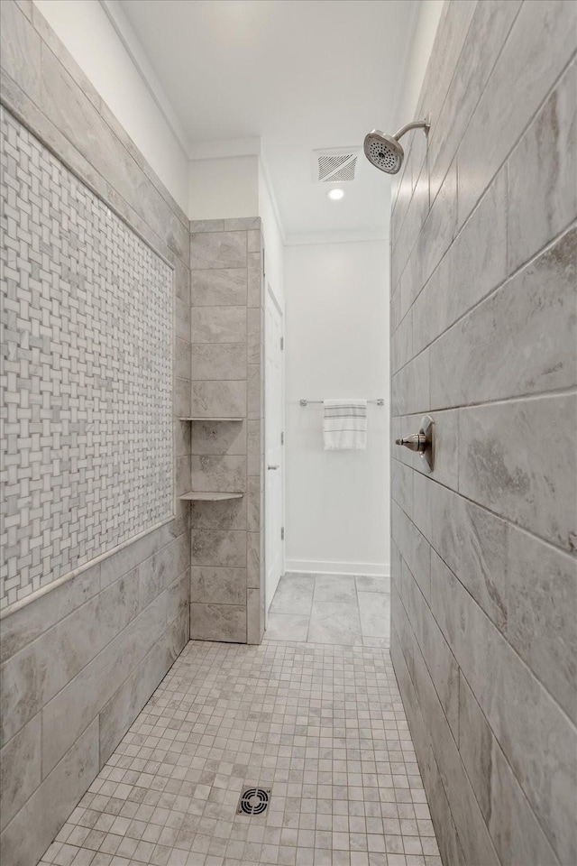 bathroom featuring ornamental molding, visible vents, and a tile shower