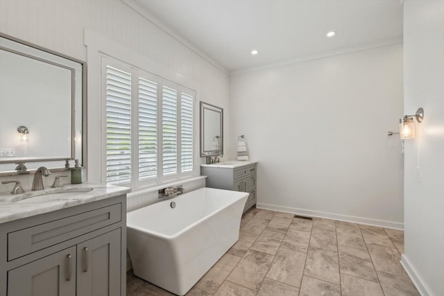 full bathroom with a freestanding tub, crown molding, two vanities, and a sink