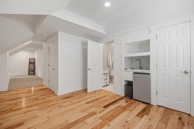 interior space with light countertops, vaulted ceiling, a sink, light wood-type flooring, and fridge