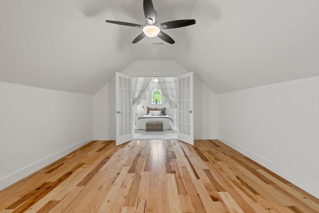 additional living space featuring baseboards, visible vents, lofted ceiling, hardwood / wood-style flooring, and french doors