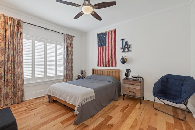 bedroom with ornamental molding, wood finished floors, visible vents, and a ceiling fan