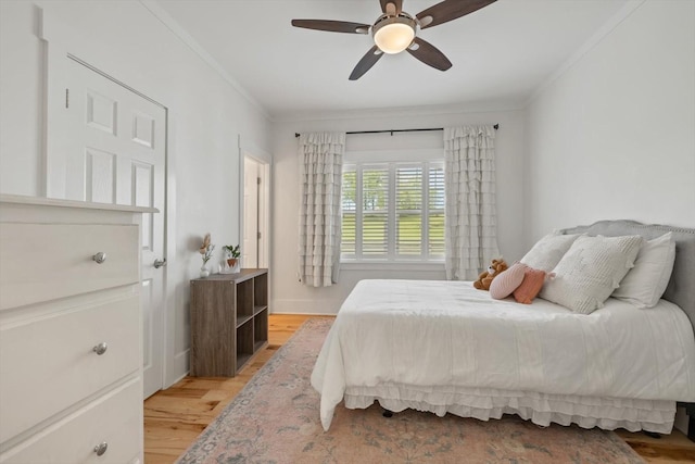 bedroom featuring light wood-style flooring, a ceiling fan, and crown molding