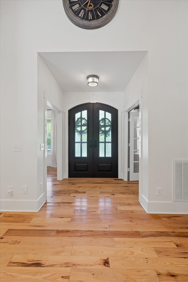 entryway featuring visible vents, arched walkways, baseboards, wood-type flooring, and french doors