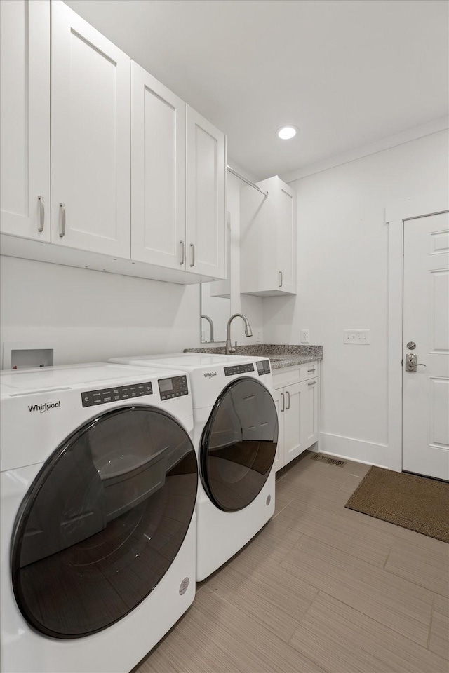 washroom with recessed lighting, cabinet space, a sink, independent washer and dryer, and baseboards