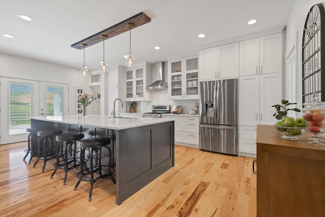 kitchen featuring stainless steel appliances, white cabinets, a sink, and wall chimney exhaust hood