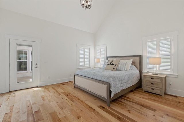 bedroom featuring light wood-type flooring, baseboards, and high vaulted ceiling