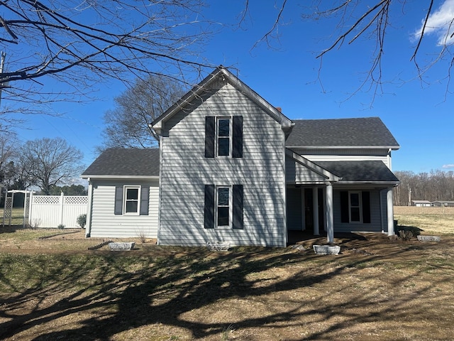 back of house with a shingled roof and fence