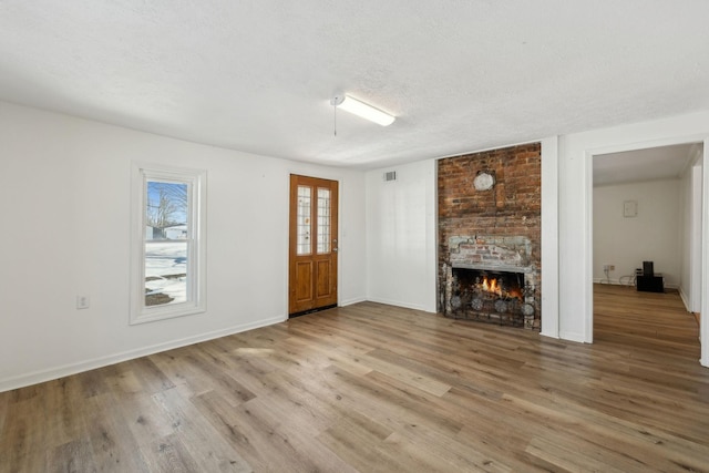 120 Wilkerson Ln, Portland, TN 37148 - unfurnished living room featuring a textured ceiling, a brick fireplace, wood finished floors, and baseboards