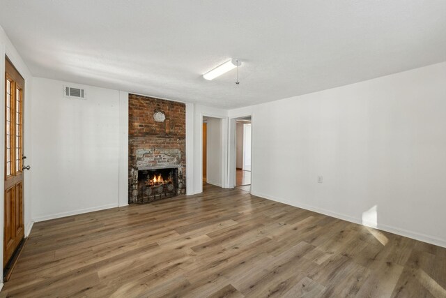 120 Wilkerson Ln, Portland, TN 37148 - unfurnished living room with a brick fireplace, baseboards, visible vents, and wood finished floors