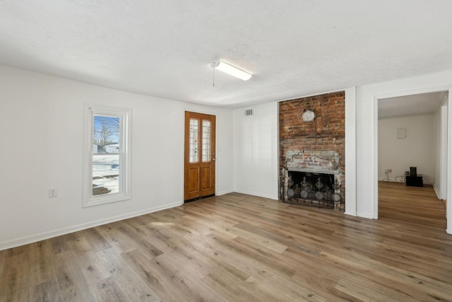 120 Wilkerson Ln, Portland, TN 37148 - unfurnished living room featuring a textured ceiling, a fireplace, wood finished floors, and baseboards