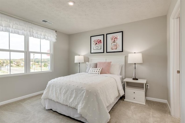 bedroom featuring visible vents, baseboards, carpet, and a textured ceiling