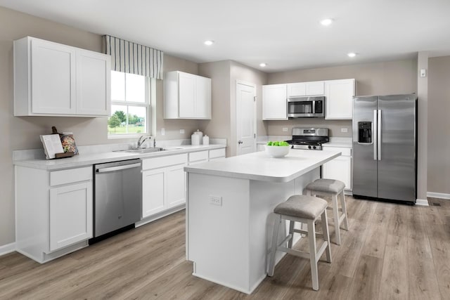 kitchen with a sink, stainless steel appliances, a breakfast bar area, and white cabinets