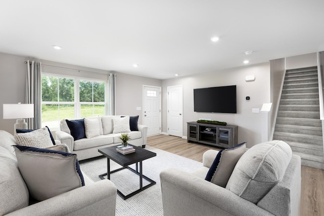 living area with light wood finished floors, recessed lighting, and stairs