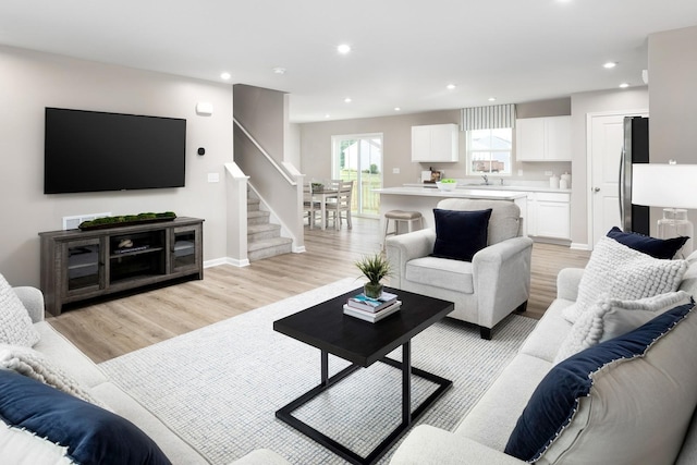 living area with stairway, recessed lighting, light wood-type flooring, and baseboards