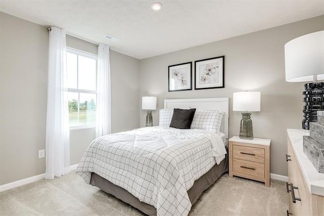 bedroom with baseboards, light carpet, and visible vents