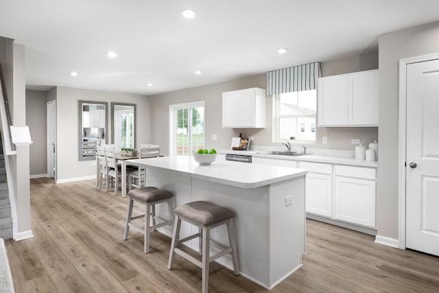 kitchen featuring recessed lighting, a sink, light wood-style floors, a kitchen bar, and a center island