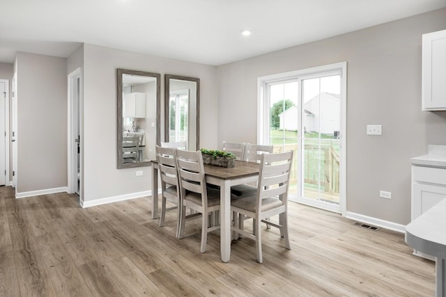 dining room featuring plenty of natural light, baseboards, and light wood finished floors