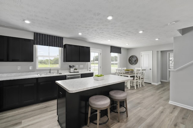 kitchen featuring light countertops, a breakfast bar area, dark cabinets, and a sink