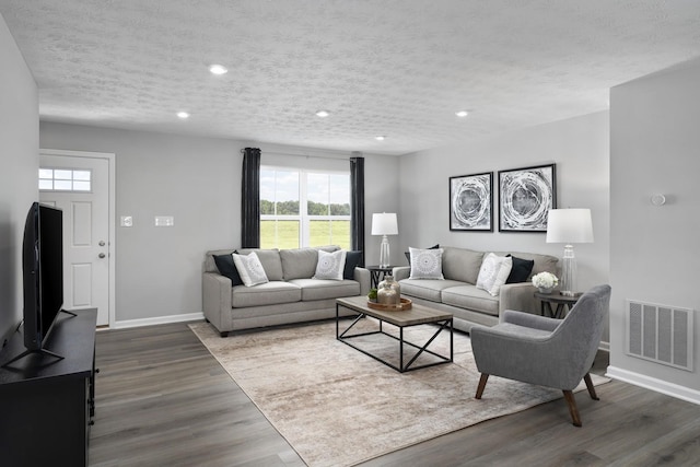 living area with visible vents, dark wood-type flooring, baseboards, recessed lighting, and a textured ceiling