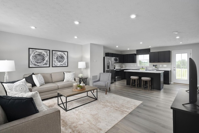 living area featuring recessed lighting, light wood-type flooring, and a textured ceiling