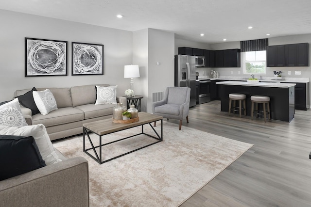 living room with recessed lighting, visible vents, and light wood-style floors