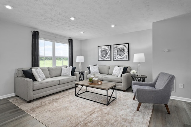 living room featuring recessed lighting, a textured ceiling, baseboards, and wood finished floors