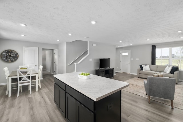 kitchen with light countertops, light wood-style flooring, dark cabinets, and a kitchen island