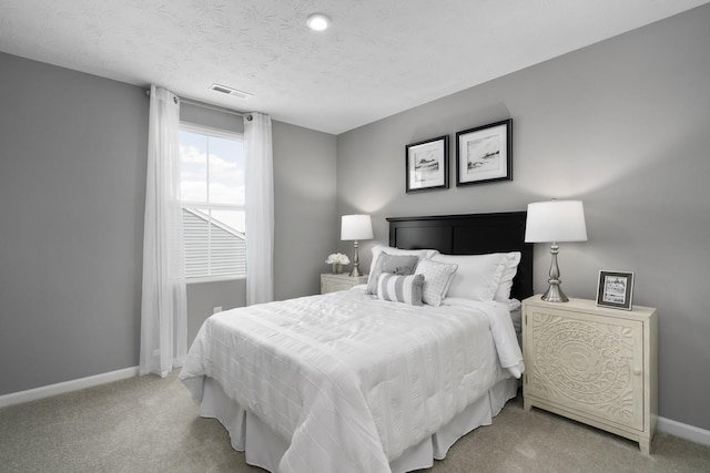 bedroom with a textured ceiling, baseboards, visible vents, and light carpet